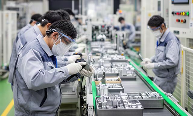 筑豊の製造工場で金属部品を検査する作業員と生産ライン